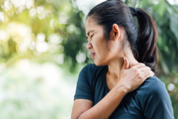 Young asian woman touching her neck while wincing in pain.